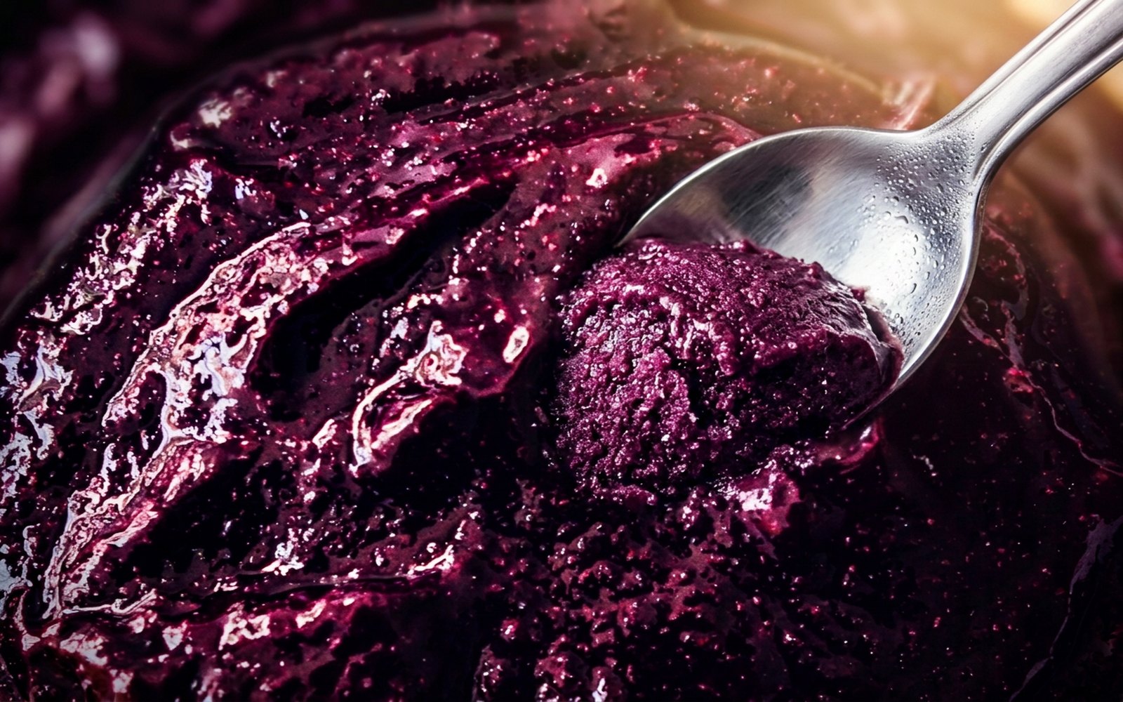 Macro do açaí AÇAIST mostrando a textura cremosa e granulada, com colher retirando uma porção