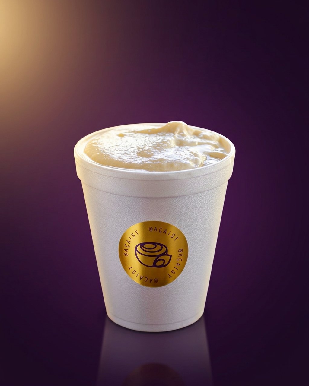 Copo AÇAIST com creme aveludado e selo dourado da marca, sobre fundo roxo profundo